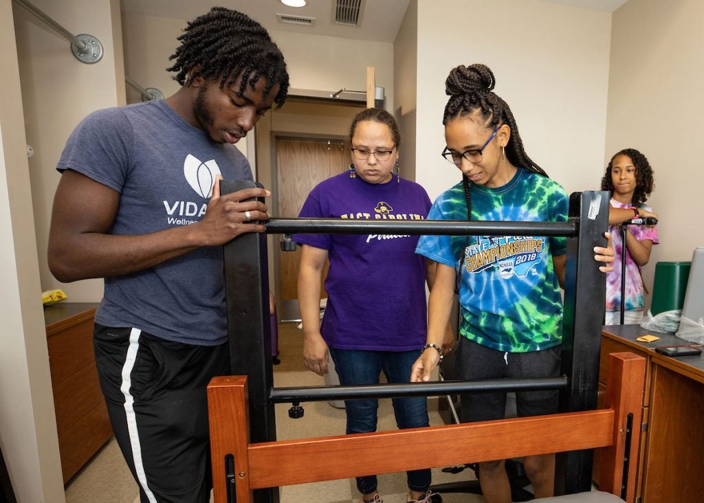 students putting together a bed in dorm room