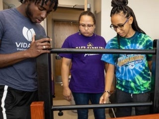 students putting together a bed in dorm room