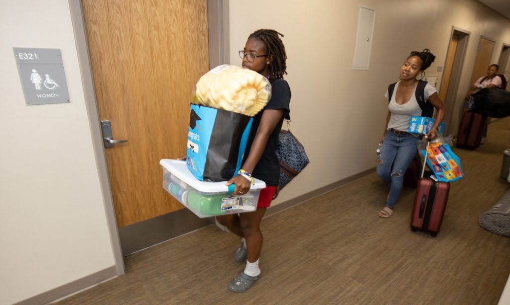 students carrying items down hallway