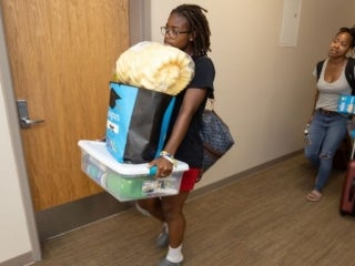 students carrying items down hallway