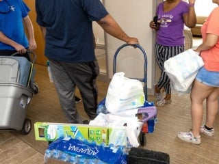 People moving items on carts in hallway