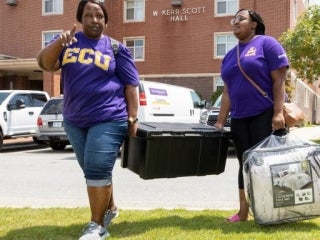 two people caring a trunk in a parking lot