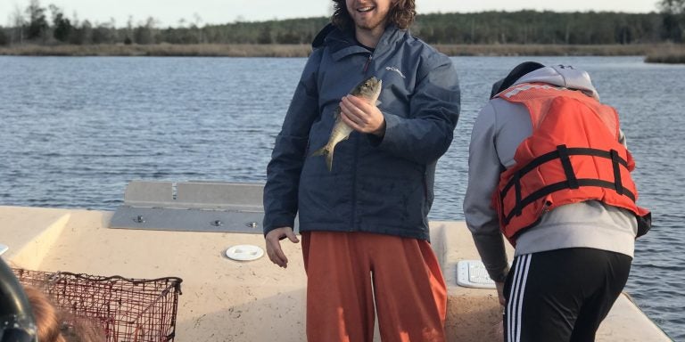 ECU student holding the menhaden. Photo taken by ECU boat captain Eric Diaddorio